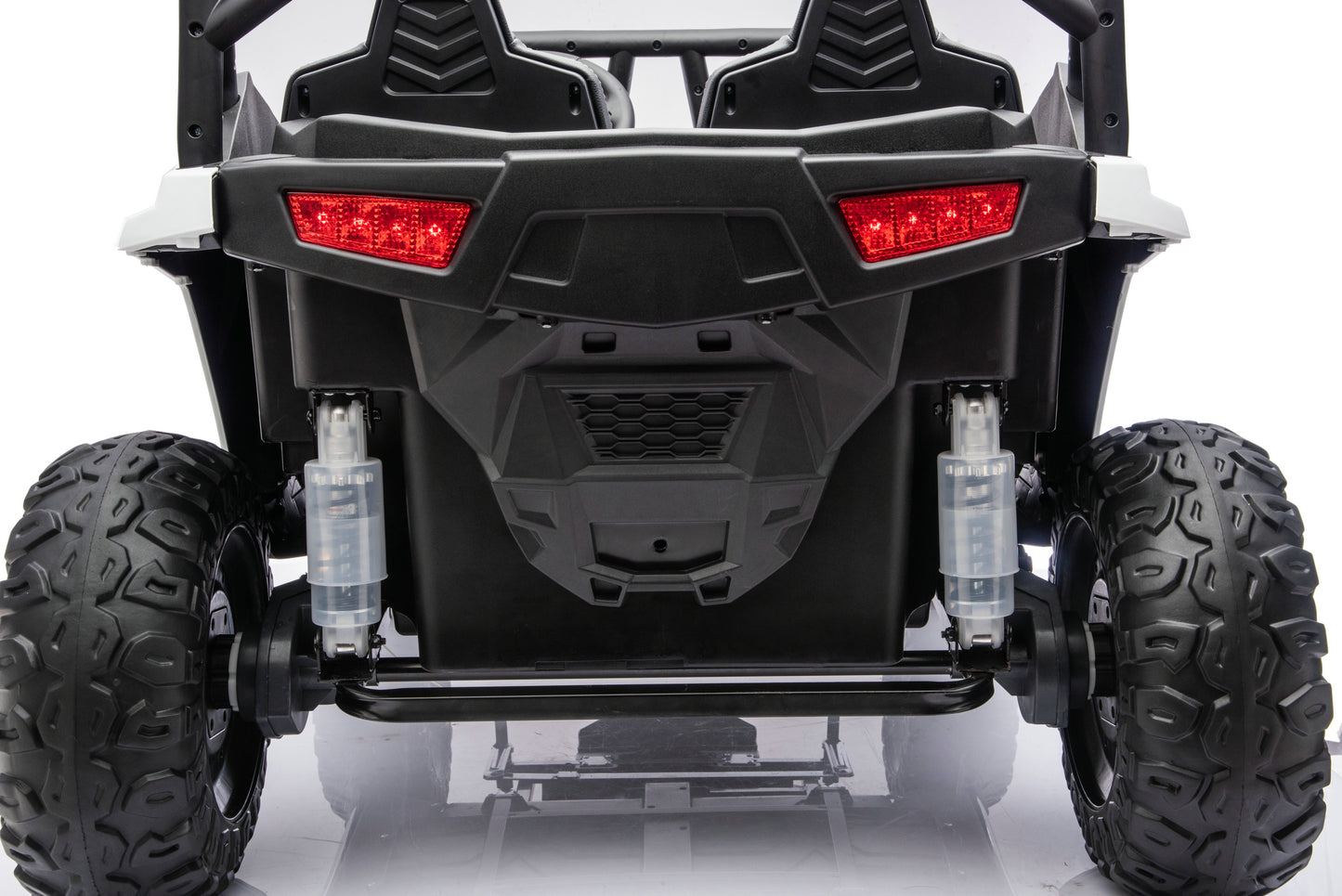 Rear view of a black and white off-road utility vehicle with large knobby tires, red taillights, and visible suspension components on a white studio background.