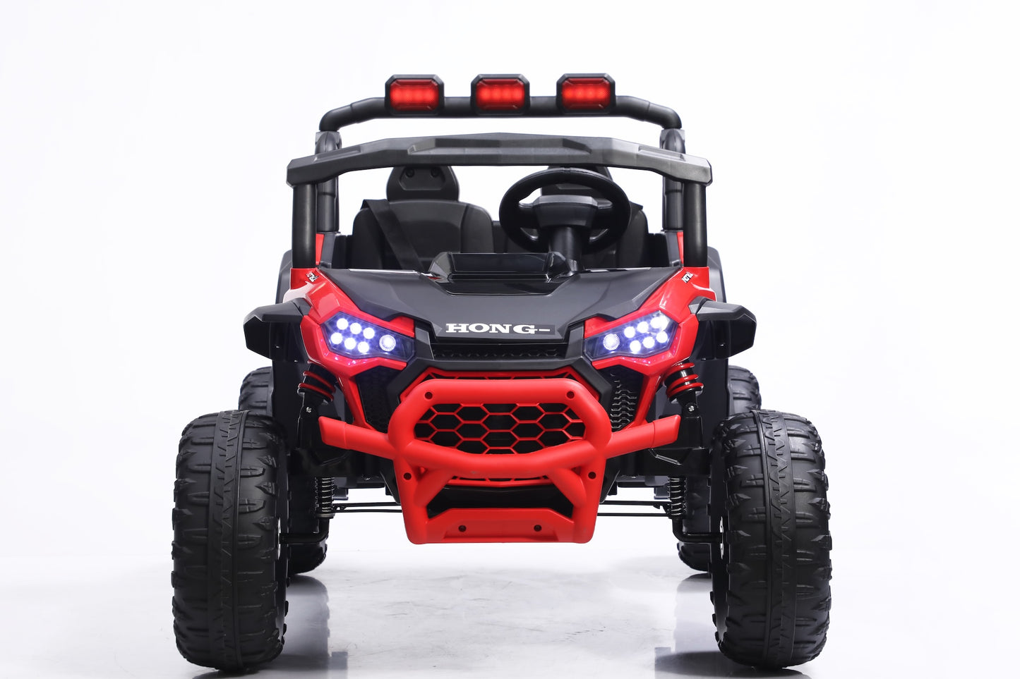 A red and black kids' ride-on utility vehicle with large off-road tires, a roll cage, and LED lights, photographed from the front on a white studio background.
