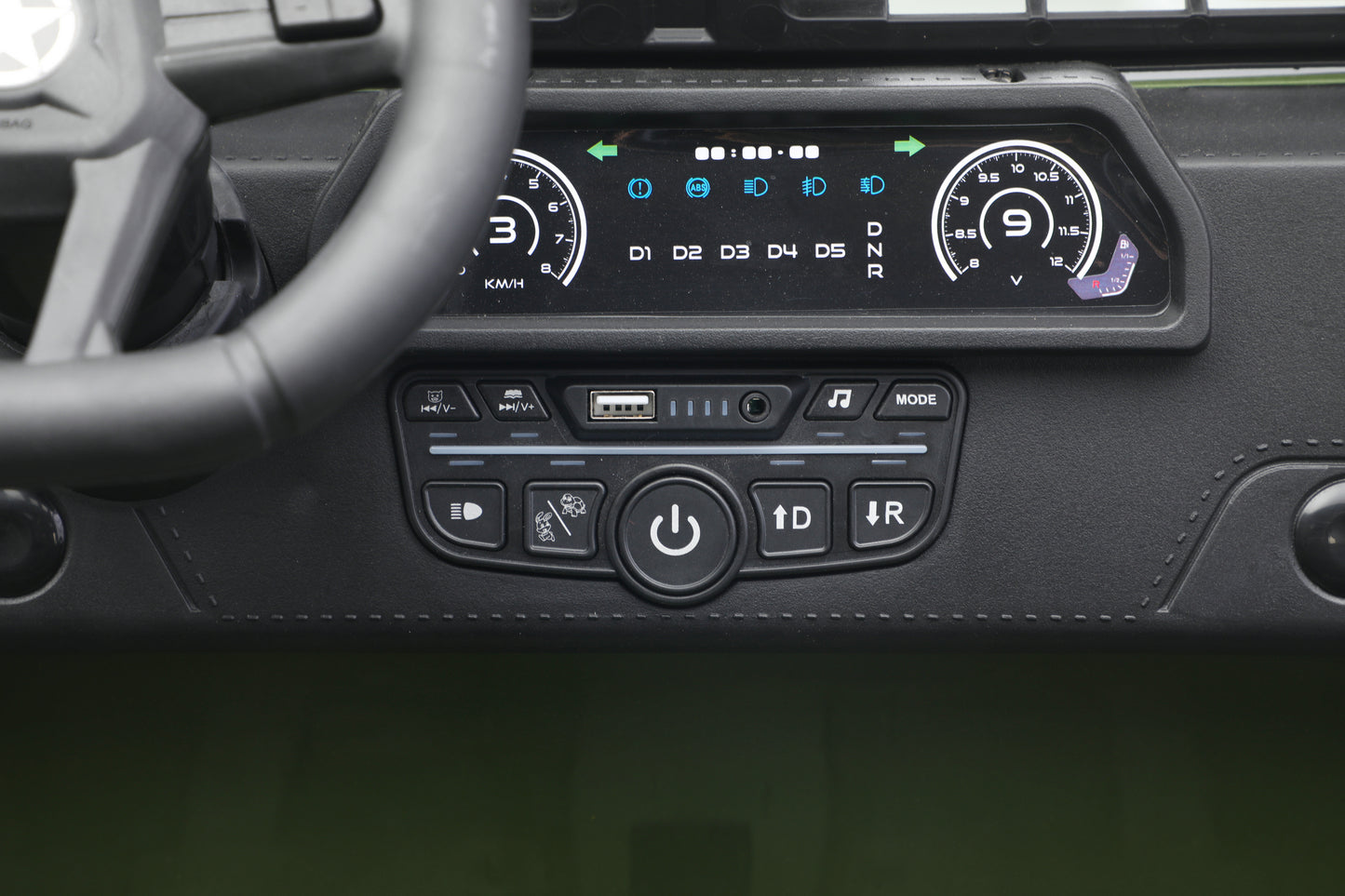 Close-up of a toy jeep 24v car's dashboard centre console showing a digital instrument display and control buttons below, with part of the steering wheel visible on the left.